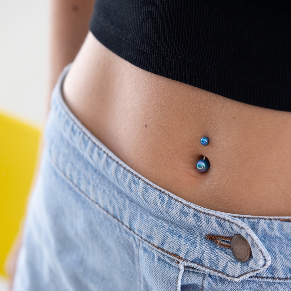 Bauchnabelpiercing mit metallischen Kugeln