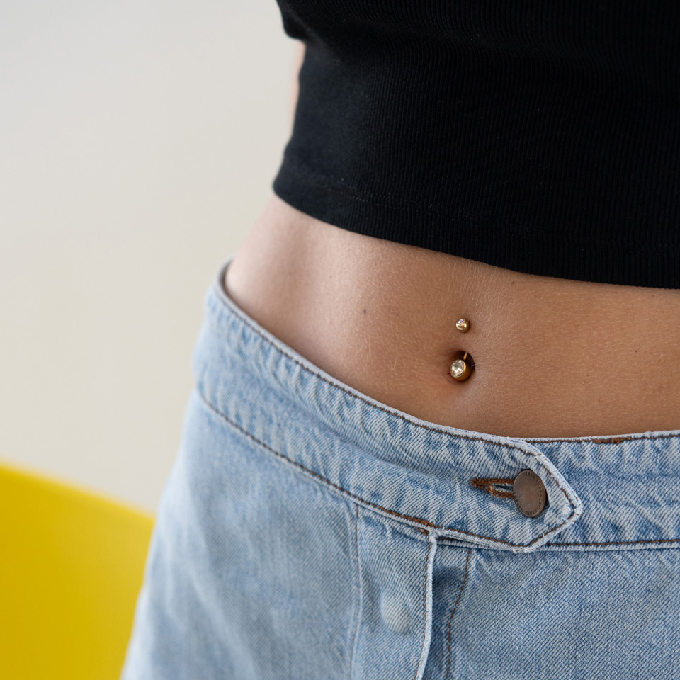 Vergoldetes Bauchnabelpiercing mit Steinen
